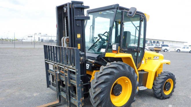 Yellow JCB forklift with forks raised in parking lot