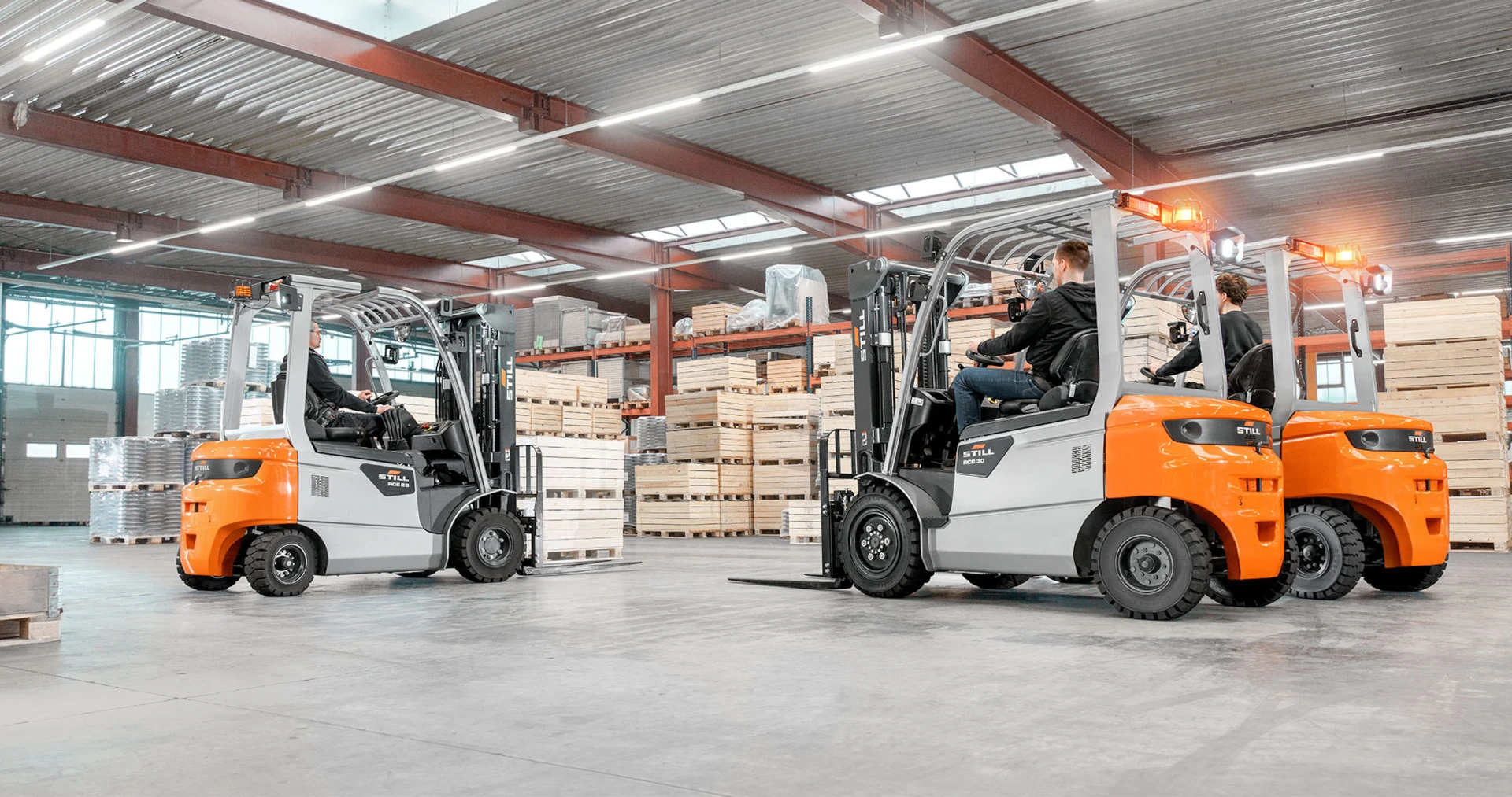 Workers operating forklifts in industrial warehouse