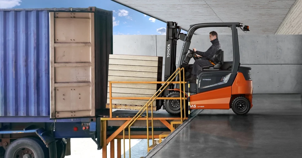 Forklift operator loading truck in industrial warehouse