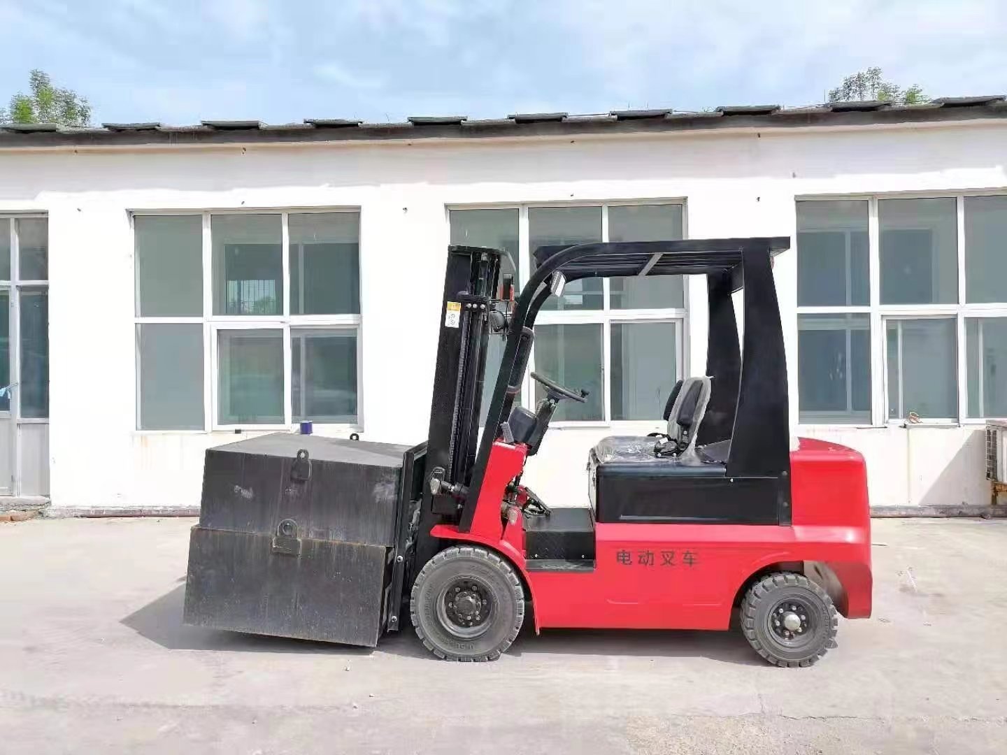 Red forklift parked outside a white building