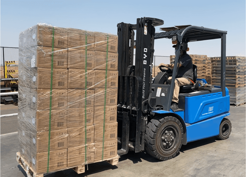 Forklift operator moving large pallet of boxed goods