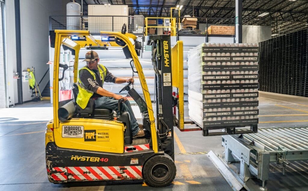 Worker operating forklift in brewery warehouse